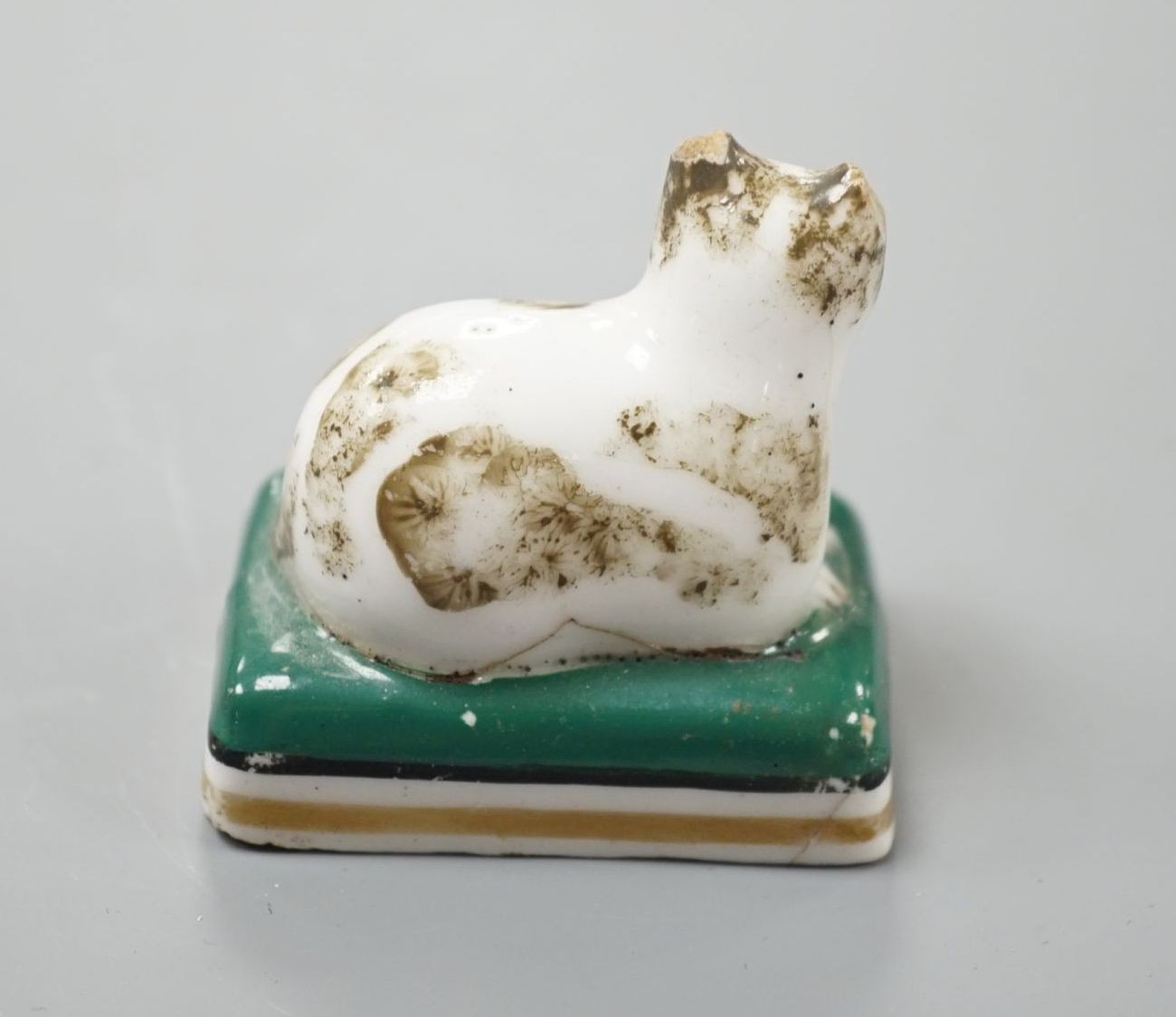 A rare English porcelain model of a recumbent cat, probably Derby c.1830, 4.5 cm long, Cf. Dennis G.Rice Cats in English porcelain, colour plate 24., Provenance: Dennis G.Rice collection